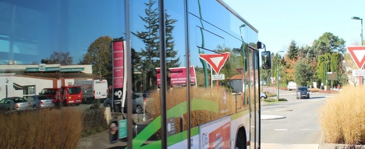 Reflet de la vie économique locale dans les vitres d'un bus, près de la place des échoppes