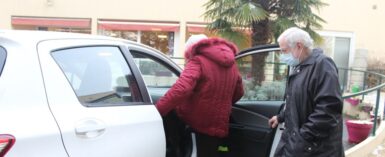 Mobilité solidaire, une femme monte dans la voiture d'un conducteur bénévole pour réaliser ses achats de première nécessité